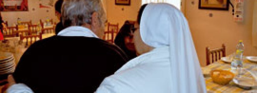 religiosa ayuda a un anciano en un centro de Cáritas