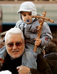 abuelo con niño pequeño lleva una cruz