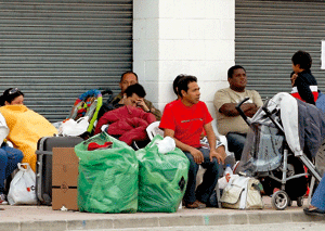 inmigrantes sentados esperando en la calle