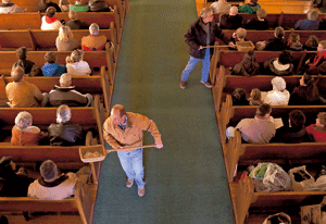dos personas pasando el cepillo en misa para recaudar dinero