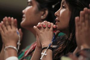 dos mujeres chinas católicas rezando con un rosario