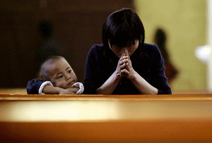 mujer y niño chinos rezando en una iglesia