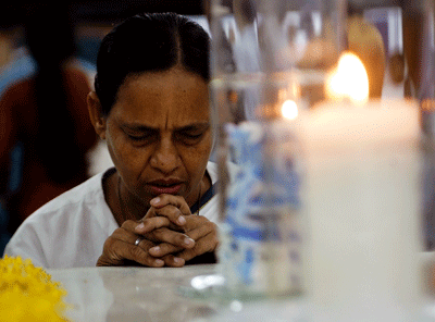 mujer rezando con las manos juntas frente a un cirio