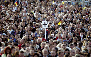 multitud de gente con un cartel con una cruz