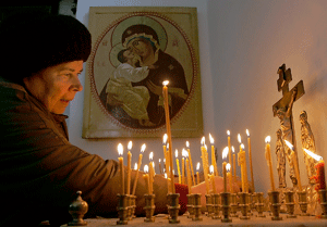 mujer cristiana ortodoxa en Bielorrusia rezando y poniendo velas
