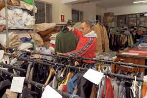 un hombre busca ropa en un ropero de Cáritas