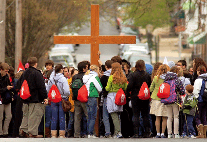 jóvenes católicos portan una cruz en procesión en la calle