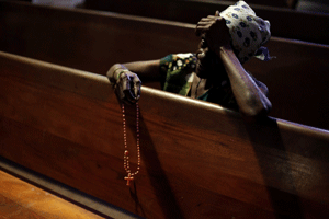 mujer reza el rosario en una iglesia en Brasil
