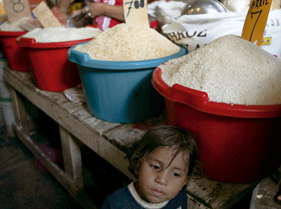 niña en un mercado vendiendo arroz