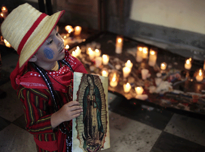 niño indígena en una Iglesia con velas