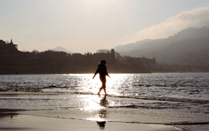chica pasea en el mar en la playa al atardecer