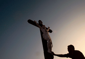 hombre reza delante de un crucifijo