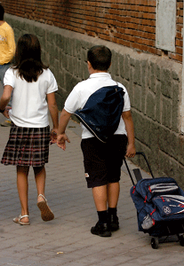 dos niños de uniforme de camino al colegio
