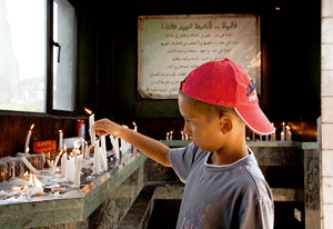 niño cristiano en Líbano enciende velas en una iglesia