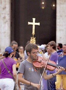 joven católico tocando el violín delante de un crucifijo