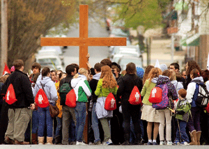 grupo de jóvenes cristianos en la calle con una cruz