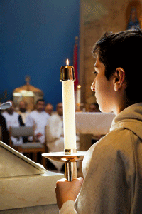 un monaguillo porta una vela durate una eucaristía