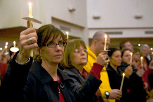 mujeres y hombre portan velas en una celebración en misa