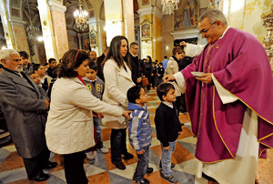 párroco durante la imposición de la ceniza a niños y fieles
