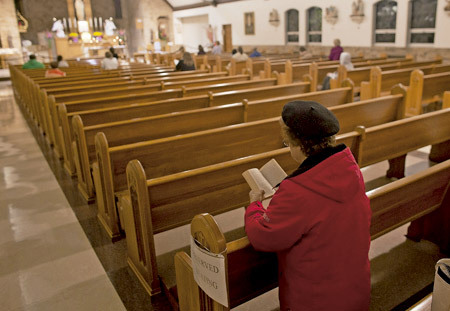 mujer rezando en una iglesia sola en el banco