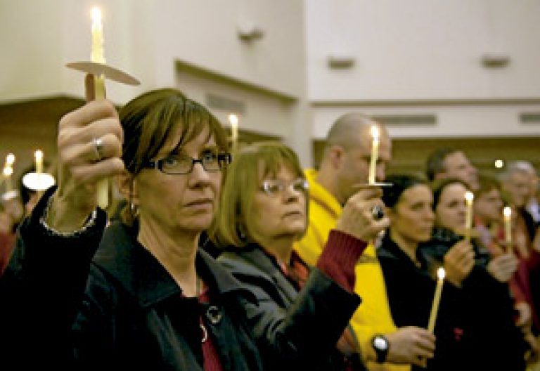 mujeres en una iglesia portan velas