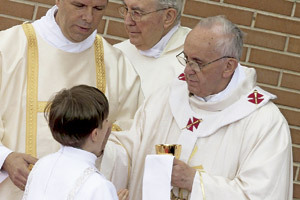 papa Francisco da la comunión a un niño en una parroquia de la periferia de Roma