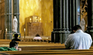 padre e hijo rezando en los bancos de una iglesia vacía