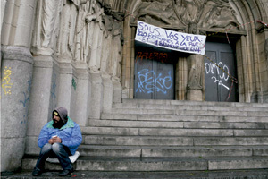mendigo sentado en la puerta de una iglesia en Bruselas