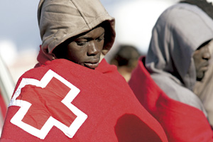 inmigrante africano con una manta de Cruz Roja