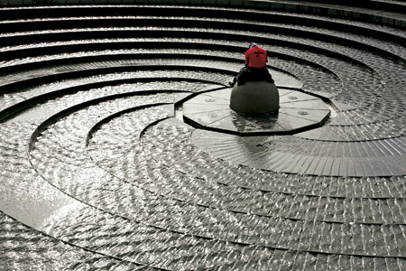 hombre sentado en medio de una fuente circular de piedra