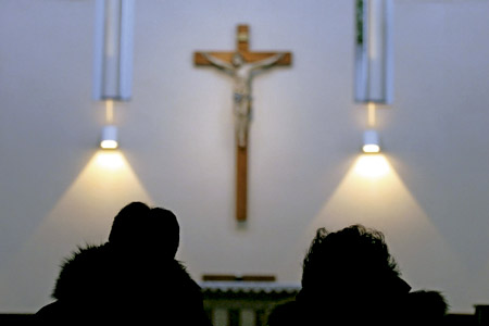dos personas en una iglesia a contraluz contemplando un crucifijo