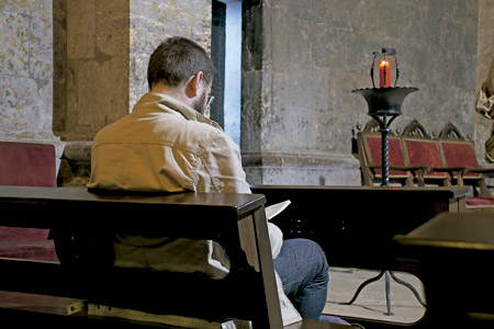 hombre en una iglesia rezando en soledad