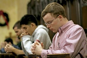 seminaristas rezando en una iglesia de rodillas