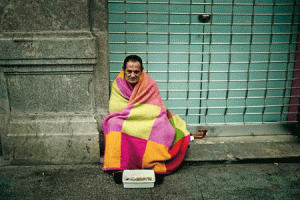 Pobre en la calle arropado por una manta de colores