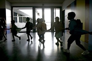 niños pequeños alumnos en la escuela en un pasillo a contraluz