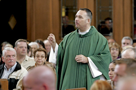 sacerdote predicando la homilía en misa de pie entre la gente