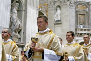 procesión de sacerdotes concelebrantes de una eucaristía con el cáliz con el cuerpo de Cristo