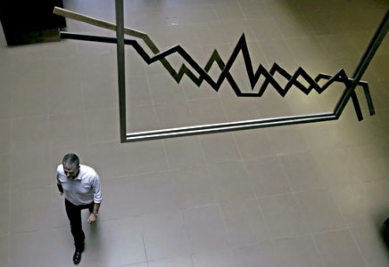 un hombre camina en la Bolsa debajo de un gráfico de resultados económicos