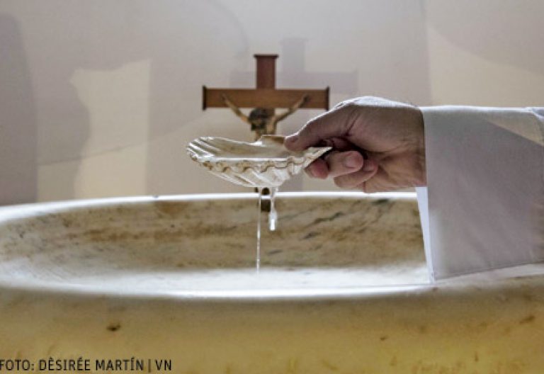 Juan Carlos Alameda, párroco de Tejina, Tenerife, en la pila bautismal con una concha con la que vierte agua. Foto Dèsirée Martín para VN