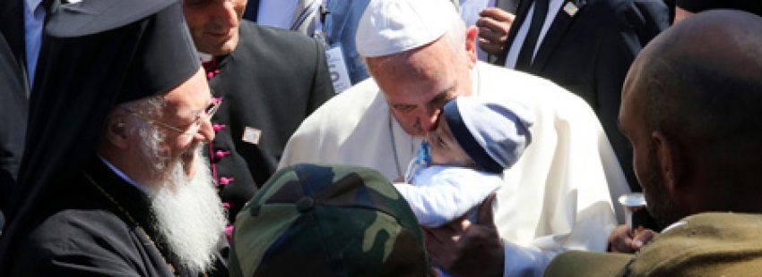 papa Francisco besa a un bebé de una familia de refugiados en el campo de Moria, Lesbos, en presencia del patriarca Bartolomé, 16 abril 2016