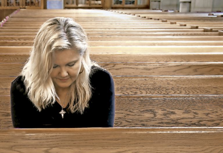 mujer sola sentada en los bancos vacíos de una iglesia