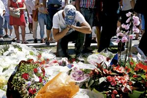 joven reza ante coronas de flores depositadas en el Paseo de los Ingleses, donde tuvo lugar el ataque en Niza 14 julio 2016