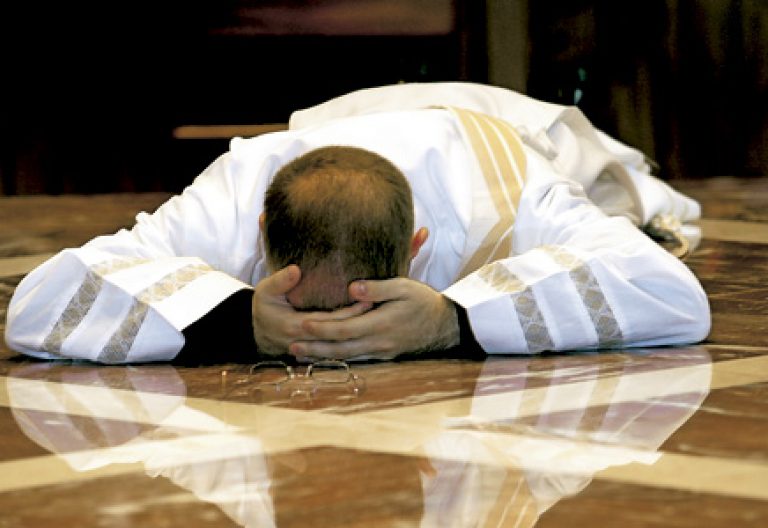sacerdote rezando tumbado en el suelo