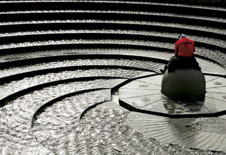 hombre rezando en una fuente de agua en forma de espiral