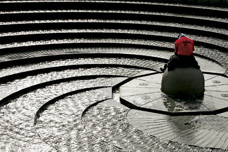 hombre rezando en una fuente de agua en forma de espiral
