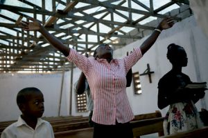 mujer reza en una iglesia devastada por el paso del huracán Matthew en Haití octubre 2016