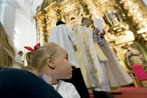 niña en brazos de su madre en una iglesia durante una misa con sacerdote