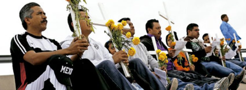 un grupo de hombres sostienen cruces durante una oración por inmigrantes fallecidos al intentar cruzar la frontera en Ciudad Juárez