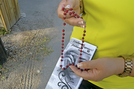 mujer con un folleto de información de un centro provida y un rosario