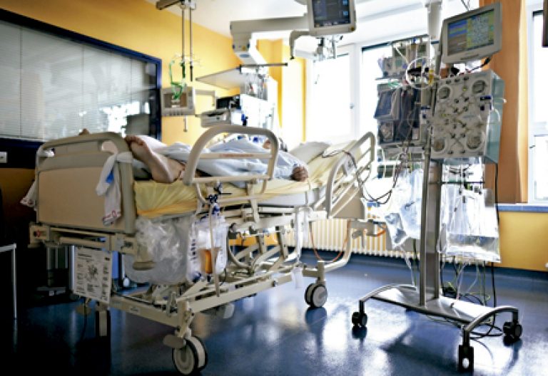paciente enfermo en una cama de hospital conectado a varios aparatos